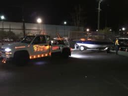 Busters Towing flatbed transporting a boat at night in Vancouver